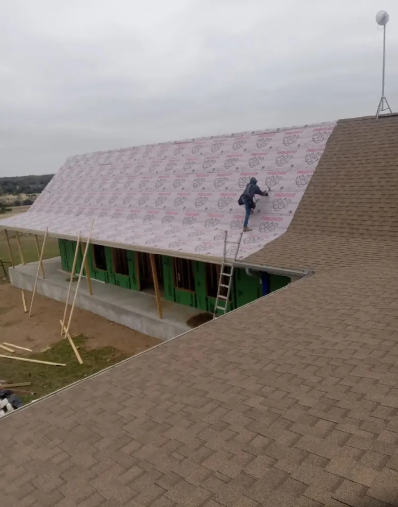 Worker preparing underlayment for a metal roof installation in Barnegat